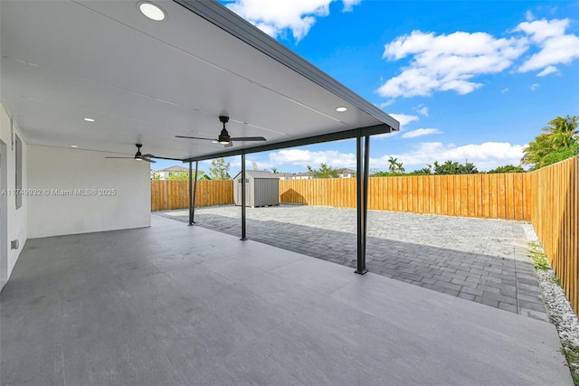 view of patio / terrace with a storage unit, an outdoor structure, a fenced backyard, and a ceiling fan