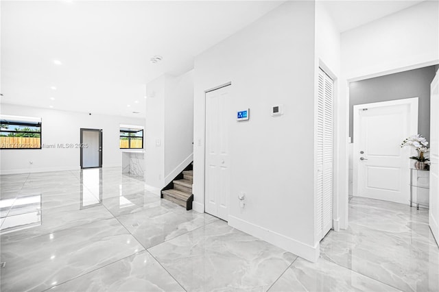 interior space featuring marble finish floor, baseboards, and stairs