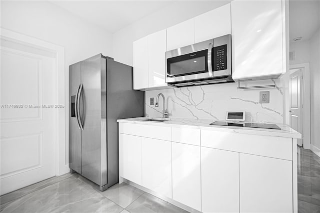 kitchen featuring a sink, white cabinets, appliances with stainless steel finishes, decorative backsplash, and modern cabinets