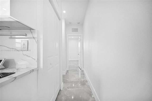 corridor with marble finish floor, visible vents, and baseboards