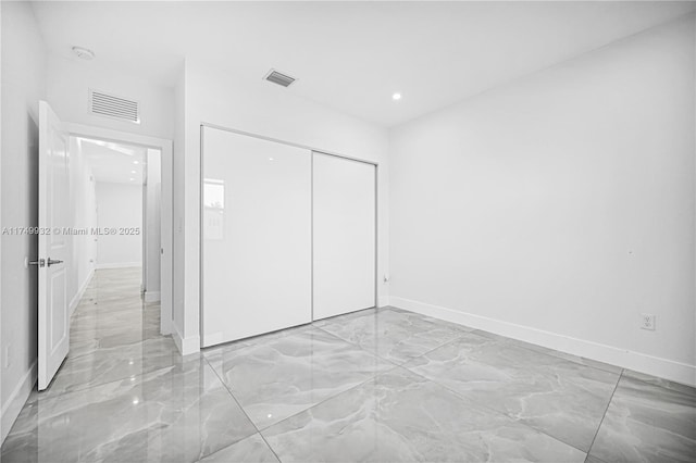 unfurnished bedroom with marble finish floor, visible vents, and a closet