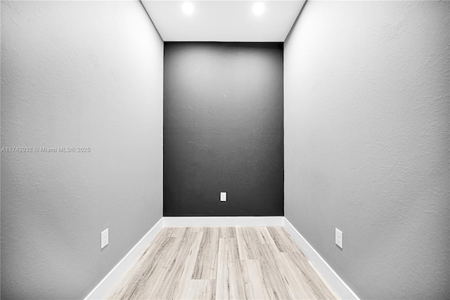 spare room featuring a textured wall, wood finished floors, and baseboards