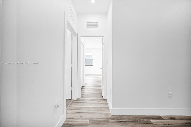 corridor featuring light wood-type flooring, visible vents, and baseboards