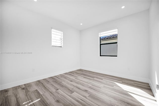 empty room with recessed lighting, a healthy amount of sunlight, light wood finished floors, and baseboards