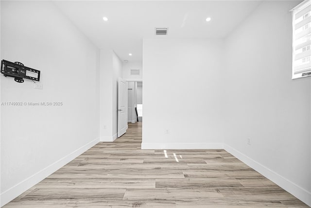 empty room featuring light wood-style floors, baseboards, visible vents, and recessed lighting