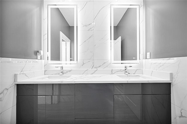 bathroom featuring double vanity, a sink, and tile walls