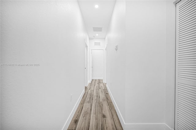 hall with light wood-style floors, visible vents, baseboards, and recessed lighting