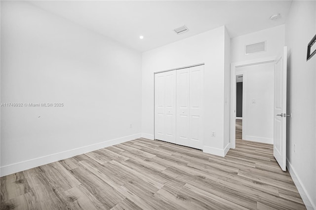 unfurnished bedroom featuring light wood finished floors, visible vents, and baseboards