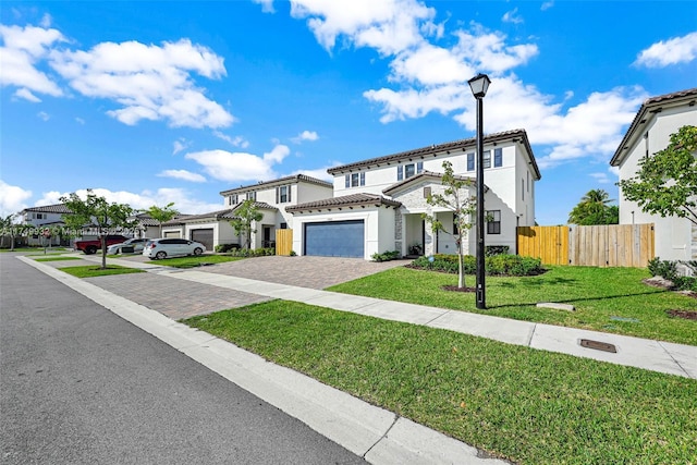 view of front of property with decorative driveway, an attached garage, fence, a residential view, and a front lawn