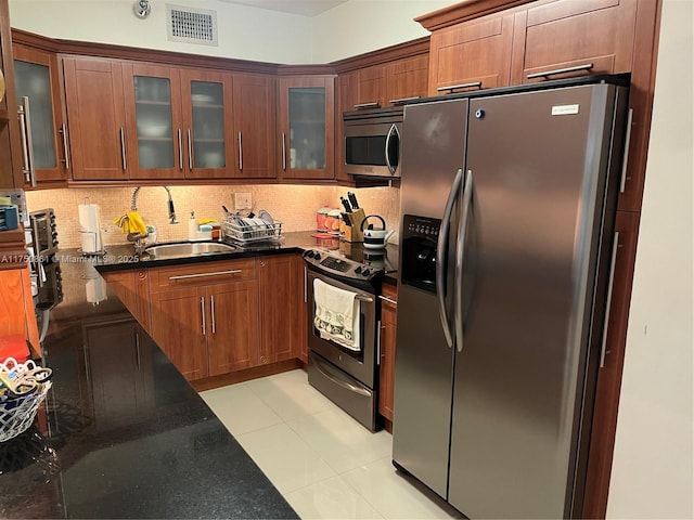 kitchen featuring light tile patterned floors, visible vents, appliances with stainless steel finishes, tasteful backsplash, and glass insert cabinets