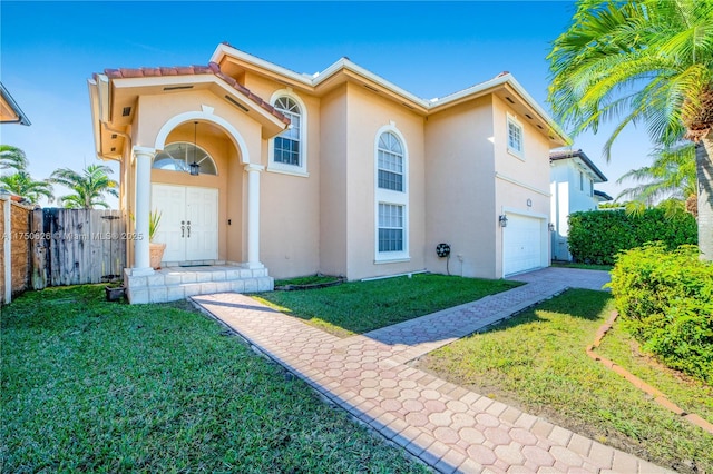 mediterranean / spanish house with an attached garage, fence, a front lawn, and stucco siding