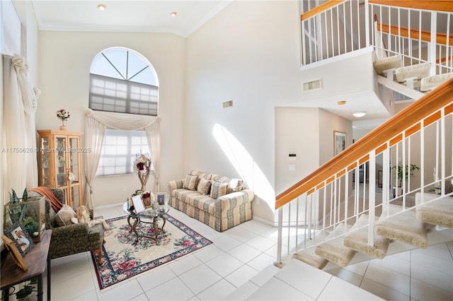 living area with light tile patterned floors, a high ceiling, visible vents, ornamental molding, and stairway