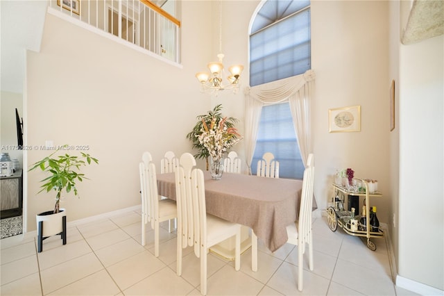 tiled dining room with a towering ceiling, baseboards, and a chandelier