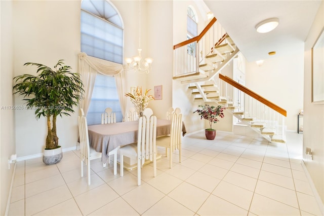 dining room with light tile patterned floors, a high ceiling, baseboards, and an inviting chandelier