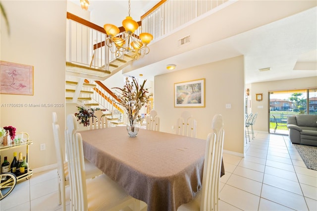 dining space with visible vents, a notable chandelier, a high ceiling, and light tile patterned floors