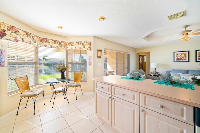 kitchen featuring light tile patterned floors, light countertops, visible vents, light brown cabinets, and baseboards