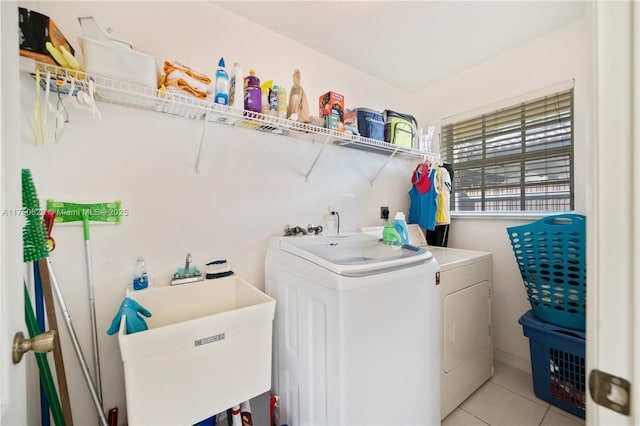 washroom featuring laundry area, light tile patterned floors, a sink, and washing machine and clothes dryer