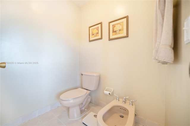 half bath with tile patterned flooring, a bidet, toilet, and baseboards