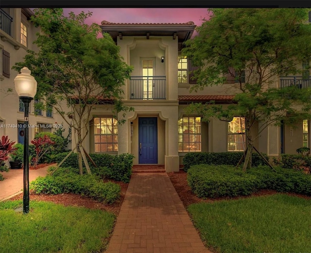 property entrance featuring a tiled roof, a balcony, and stucco siding