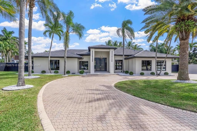 prairie-style home featuring decorative driveway, a front lawn, and stucco siding