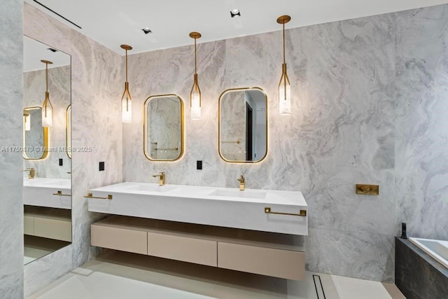 full bath featuring double vanity, a tub with marble appearance, a sink, and tile walls