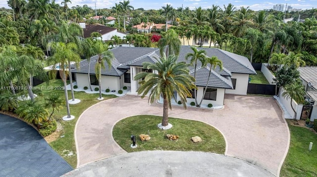 view of front of property featuring a tiled roof, a front lawn, decorative driveway, and stucco siding