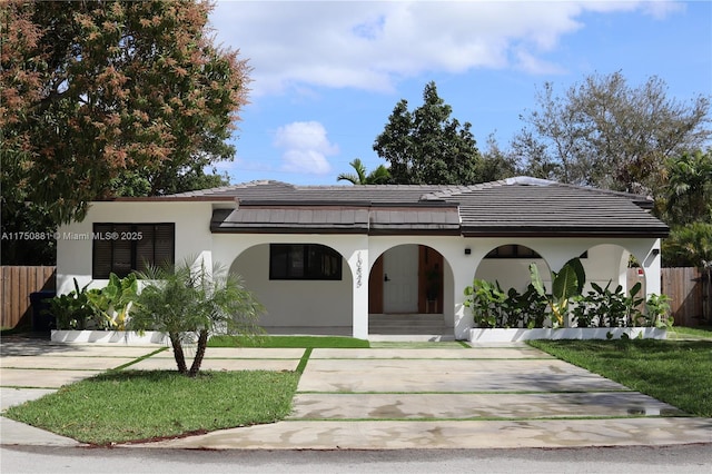 view of front of home with fence, a tiled roof, and stucco siding