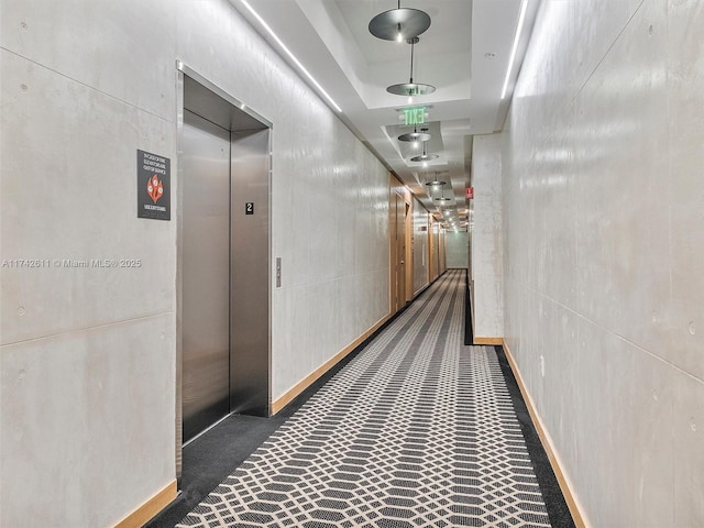 hall featuring a raised ceiling and elevator