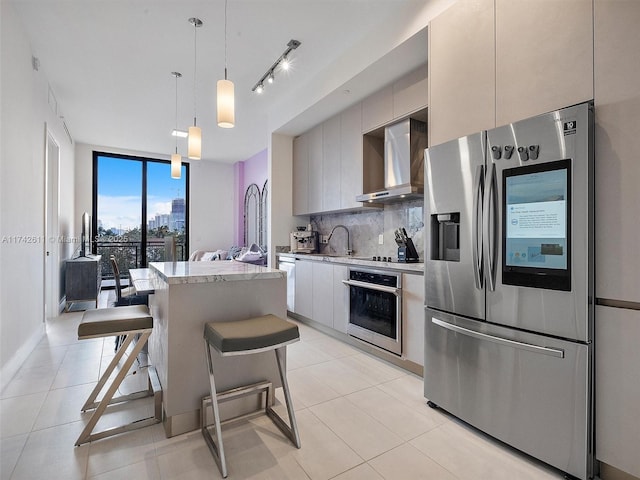 kitchen featuring a center island, hanging light fixtures, decorative backsplash, appliances with stainless steel finishes, and wall chimney exhaust hood