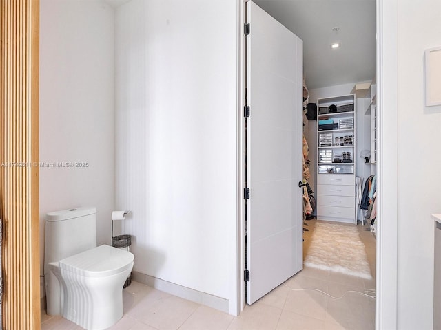 bathroom with a closet, tile patterned flooring, and toilet