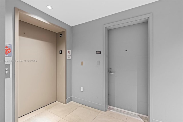 corridor featuring elevator and light tile patterned flooring