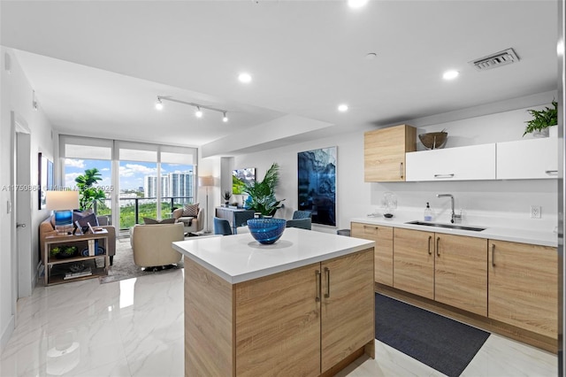 kitchen featuring a sink, a kitchen island, white cabinetry, light countertops, and modern cabinets