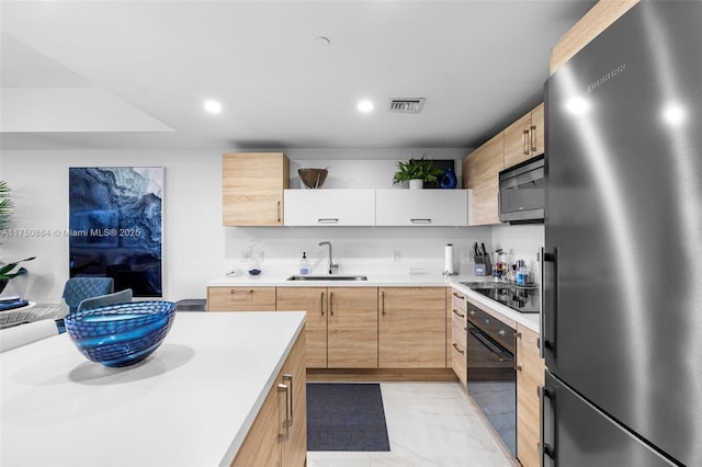 kitchen with light countertops, a sink, black appliances, and light brown cabinetry