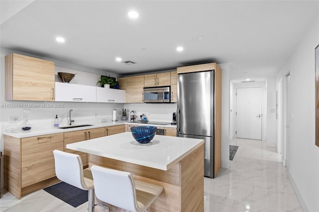 kitchen with marble finish floor, stainless steel appliances, light countertops, a sink, and a kitchen island