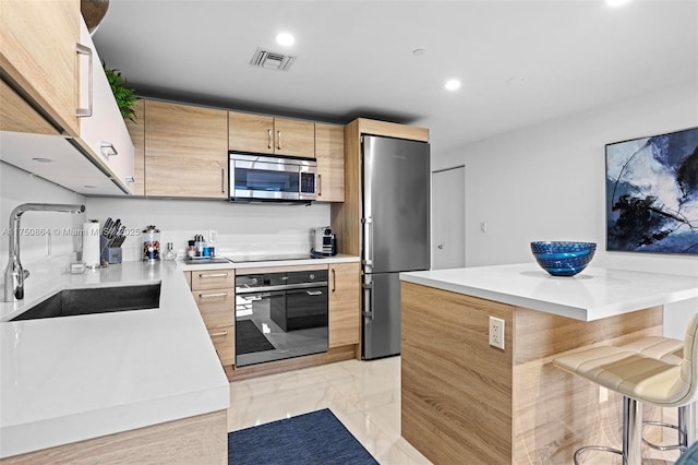 kitchen featuring a breakfast bar area, a sink, marble finish floor, light countertops, and black appliances