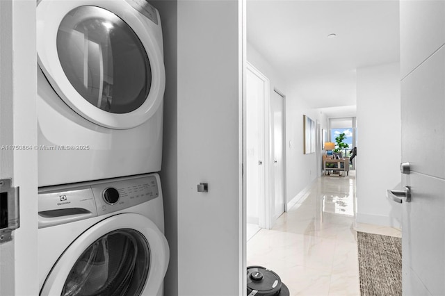 washroom with marble finish floor, stacked washer and dryer, laundry area, and baseboards