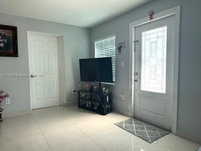 tiled entrance foyer featuring plenty of natural light and baseboards