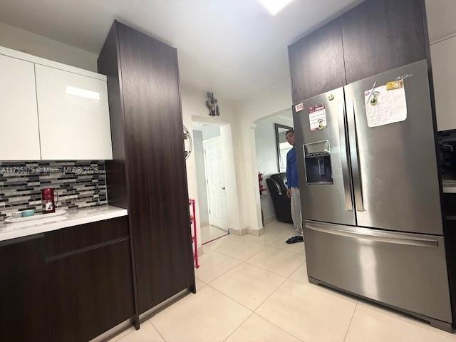 kitchen with light tile patterned floors, light countertops, backsplash, modern cabinets, and stainless steel fridge