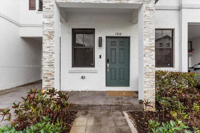 doorway to property featuring stone siding and stucco siding