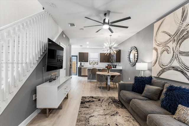 living area featuring light wood-style floors, visible vents, baseboards, and ceiling fan with notable chandelier