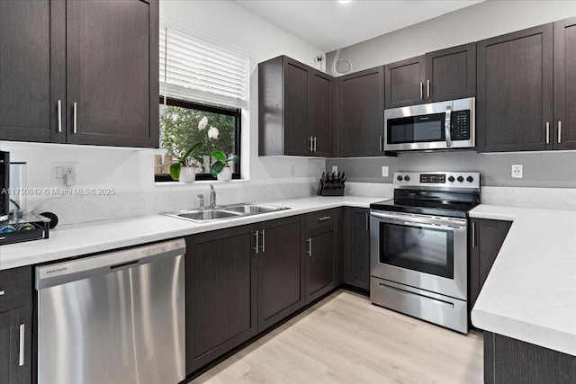 kitchen featuring dark brown cabinetry, appliances with stainless steel finishes, light countertops, and a sink