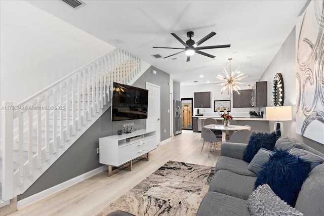 living area with visible vents, baseboards, light wood-style flooring, stairs, and a chandelier