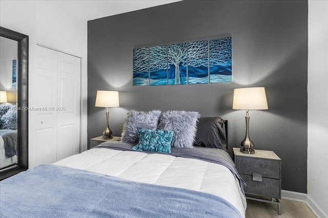 bedroom with a closet, wood finished floors, and baseboards