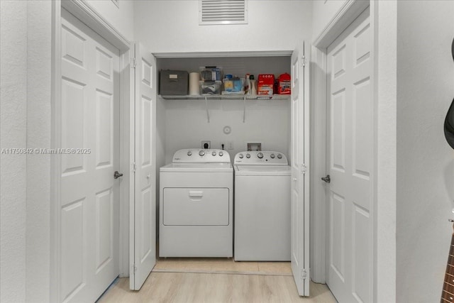 laundry room featuring light wood-type flooring, laundry area, and washer and clothes dryer