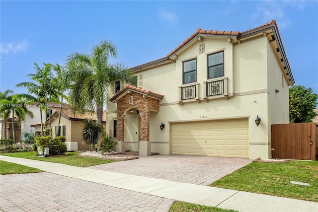 mediterranean / spanish home with a garage, a tile roof, and stucco siding