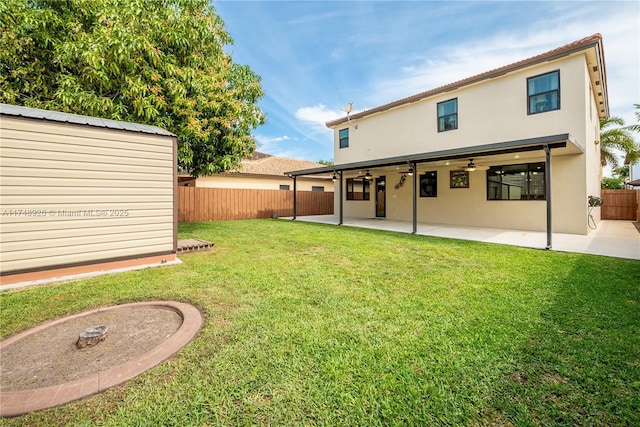 back of property with ceiling fan, a patio area, a fenced backyard, a yard, and stucco siding