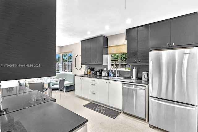 kitchen with decorative backsplash, dark countertops, stainless steel appliances, a sink, and recessed lighting