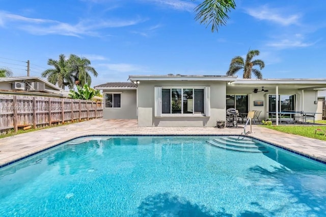 rear view of house with a patio area, fence, a fenced in pool, and stucco siding