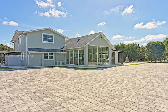 rear view of house with a shingled roof, fence, and stucco siding