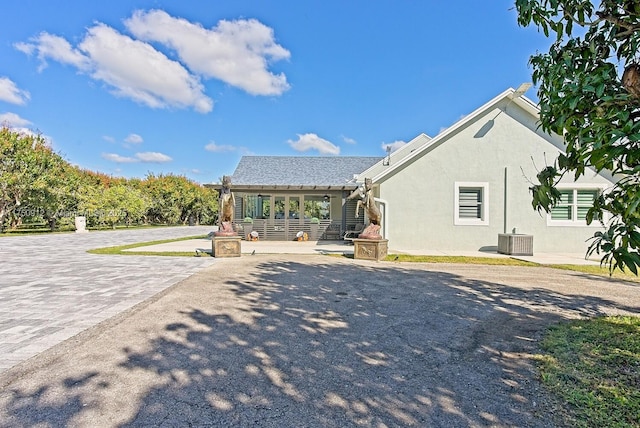 view of front of property with a patio, cooling unit, and stucco siding